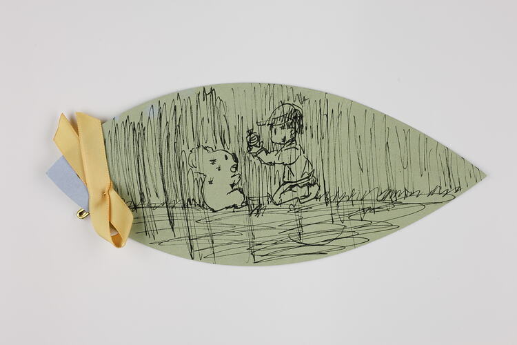 Green paper leaf with black ink sketch of koala and child. Yellow ribbon tag.