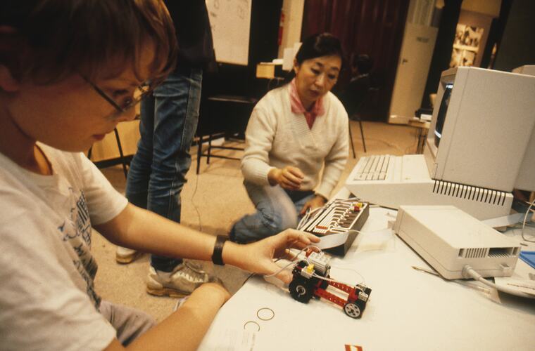 Teacher and student working with a Lego vehicle and computer.