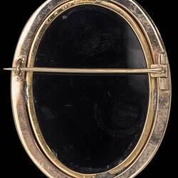 Back of Oval brooch, black set in gold border with horizontal pin.