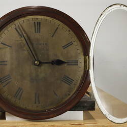 Round clock face with glass cover open.
