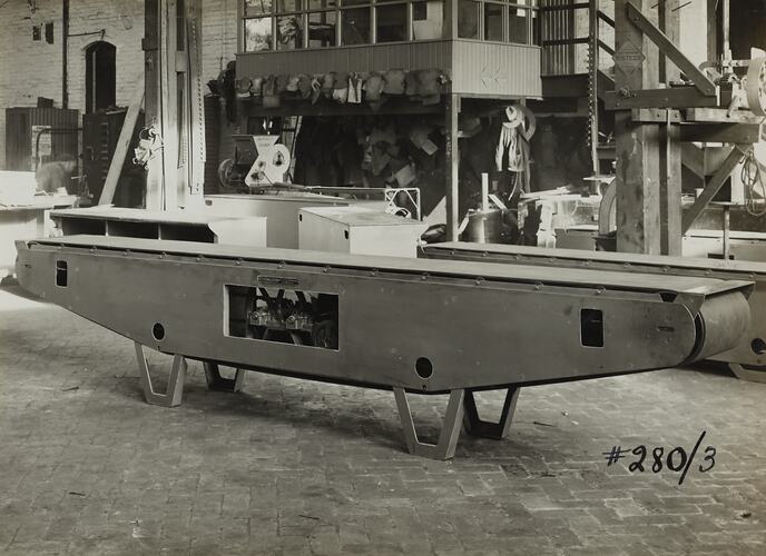 Factory setting with conveyor bench in front and raised office area at back.