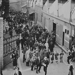 Black and white photo of workers leaving a factory.
