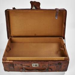 Worn brown leather suitcase with buckles. Lid open.