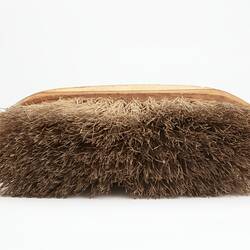 Oval shaped light brown wooden brush with off-white bristles.