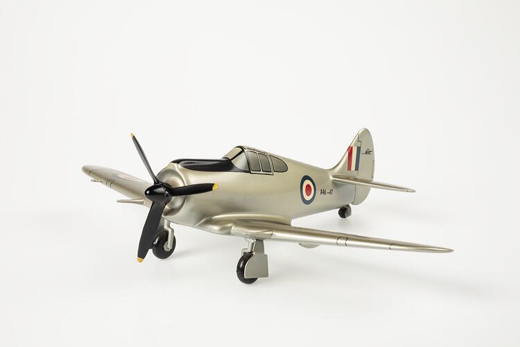 Model aeroplane, silver with a black propeller and wheels.