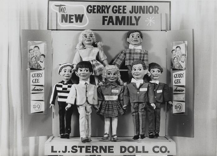 Promotional image of seven Gerry Gee Junior Family dolls. Posters frame dolls.