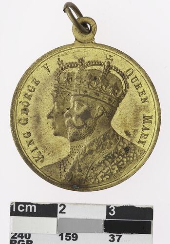 Round gold coloured medal with profile of a man and woman with crowns, text surrounding.