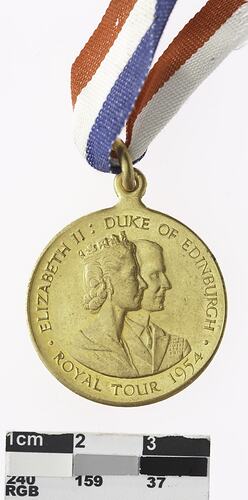 Round bronze medal with profile of man and crowned woman, with red, white and blue ribbon attached.