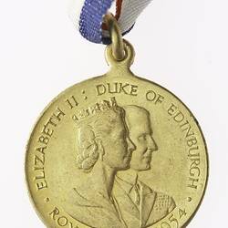 Round bronze medal with profile of man and crowned woman, with red, white and blue ribbon attached.