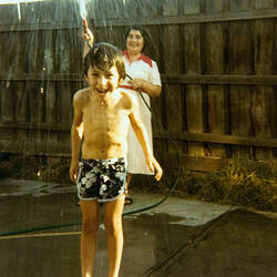 Digital Photograph - Woman Spraying Boy with Hose, Backyard, Footscray, circa 1980
