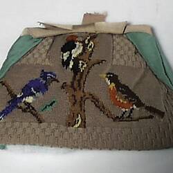 Tea cosy decorated with three birds on branches.