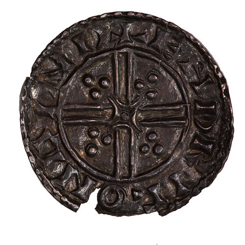 Coin, round, short cross voided below small quadrilateral with curved arma and trefoils at its points.