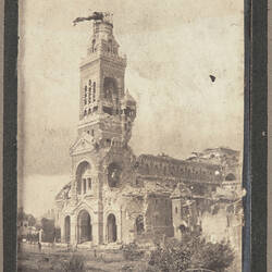 Partially destroyed stone building with attached bell tower still standing.
