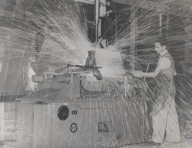 A man is operating a welding machine which is showering masses of sparks.