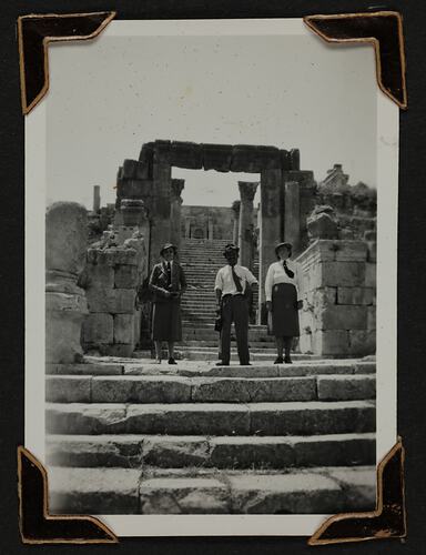 Three people in front of ancient ruins.