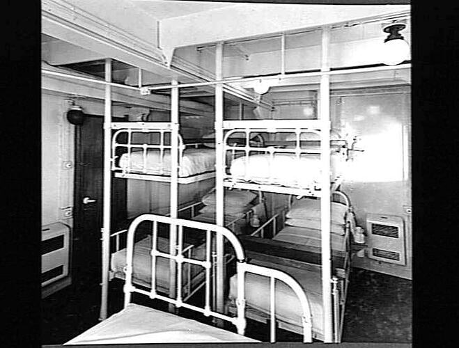 Two sets of metal bunk beds on ship.