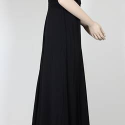 Side view, long black dress with elbow sleeves.