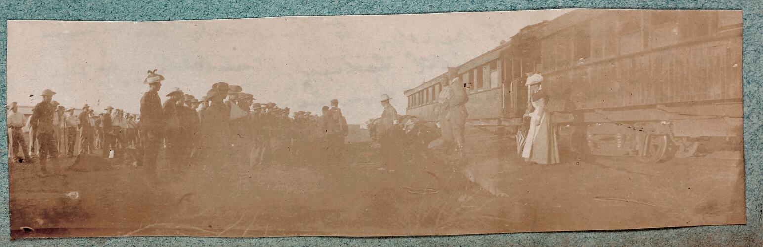 Soldiers standing in rows near train, woman standing by train facing soldiers.