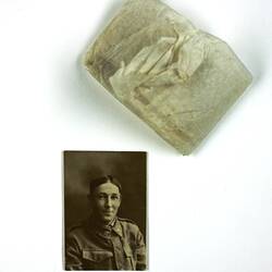 Photograph of man in uniform with paper packaging above.