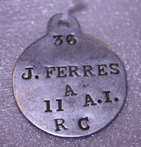 Round silver metal tag with text.