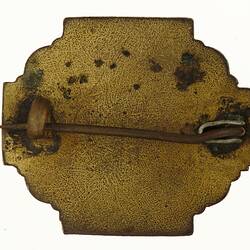 Back of copper badge with pin.