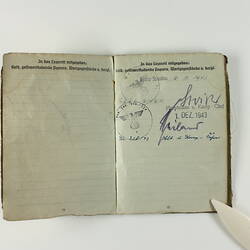 Open book page with printed text, with two stamp marks and signatures on left page.