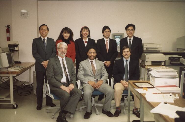 Group portrait in office with computers and printers.