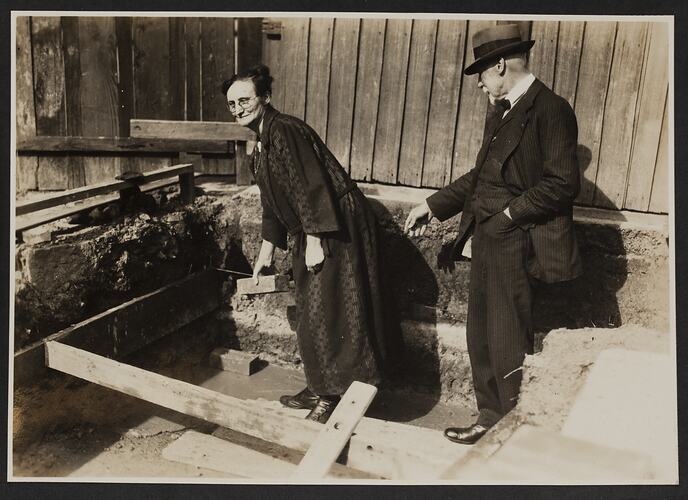 Woman with brick and man on construction site.