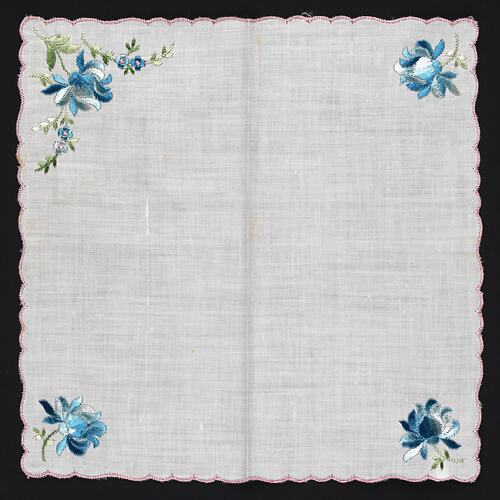 Unfolded handkerchief with blue flowers embroidered at corners.