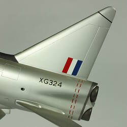 Silver model aeroplane. Detail of tail. Has small red, white and blue painted flag.
