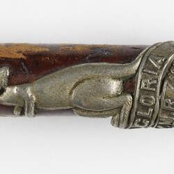 Detail of leather riding crop handle with silver cap and kangaroo emblem.