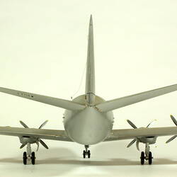 Silver model aeroplane with two propellers on each wing. Back view.