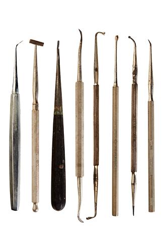 Eight varied stainless steel dental instruments.