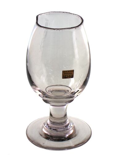 Partially formed wine glass, clear glass. Base is complete and is circular in shape. The body is elongated tear drop shape with a crazed, slightly rounded rim.