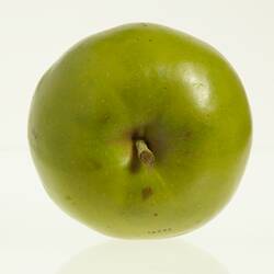 Wax model of an apple painted green. Has short stem. Top view.