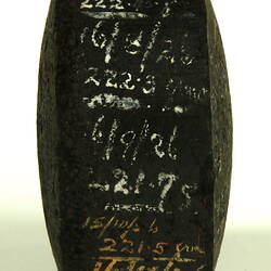 Black cylinder on side with white handwritten inscription.