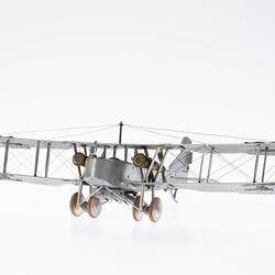 Model of a bi-plane made mostly of aluminium sheet metal. It has two pairs of wheels at front. Front view.