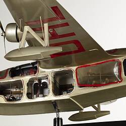 Green-silver model aeroplane on stand. Cutaways on side show interior. Close up of front section.