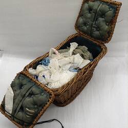 Open twin lid woven sewing basket with materials.