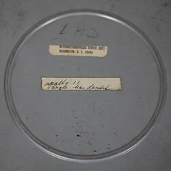 Round metal film canister. Two labels with text. Detail.