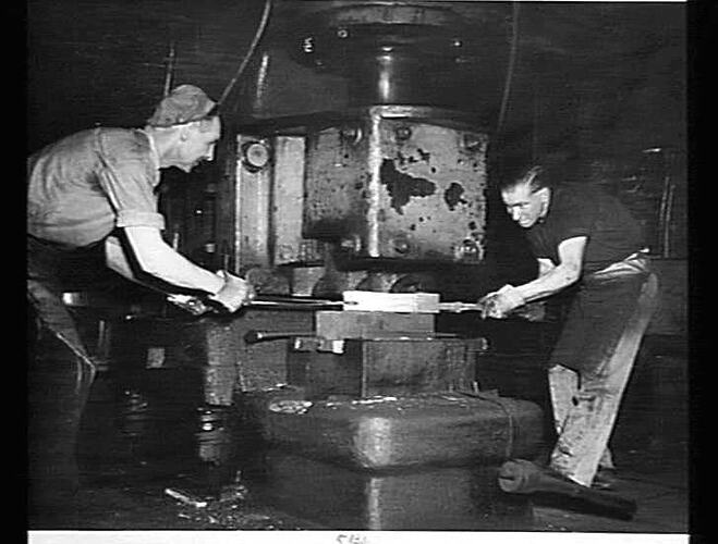 "OUR COVER - BLACKSMITHS JACK HOPE (LEFT) AND MERV BROOKS AT WORK, WITH THE ASSSISTANCE OF A LARGE PNEUMATIC FORGING MACHINE: `SUNSHINE REVIEW': DEC 1950"