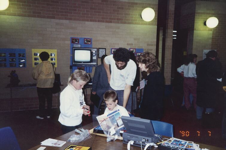 Adult and students working on a computer.