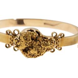 Gold bangle (bracelet) featuring a large gold nugget. Fine chain at right side.