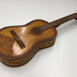 Brown wooden mandolin base with carved decorations on body.