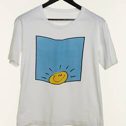 White t-shirt with blue square featuring a yellow smiling 'sunshine' face at base.