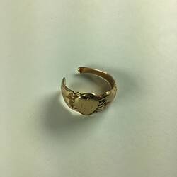 Broken women's gold ring with two clasped hands around a central love heart, inscribed with the worn cursive letters GS.