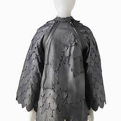 Back view of short shift-style dress made from irregular pieces of pewter grey leather to resemble reptilian scales.