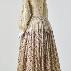 Cream muslin dress, high neck, long sleeves, banded waist, full length gathered skirt. Bustle. Back.
