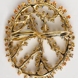 Underside view of large-scale, two-fingered, open work gold ring set with multicoloured microplastics.