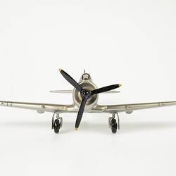 Front view of model aeroplane, silver with a black propeller and wheels.